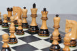 Burnt boxwood chess pieces set up for play on the included 55cm poplar and white erable board