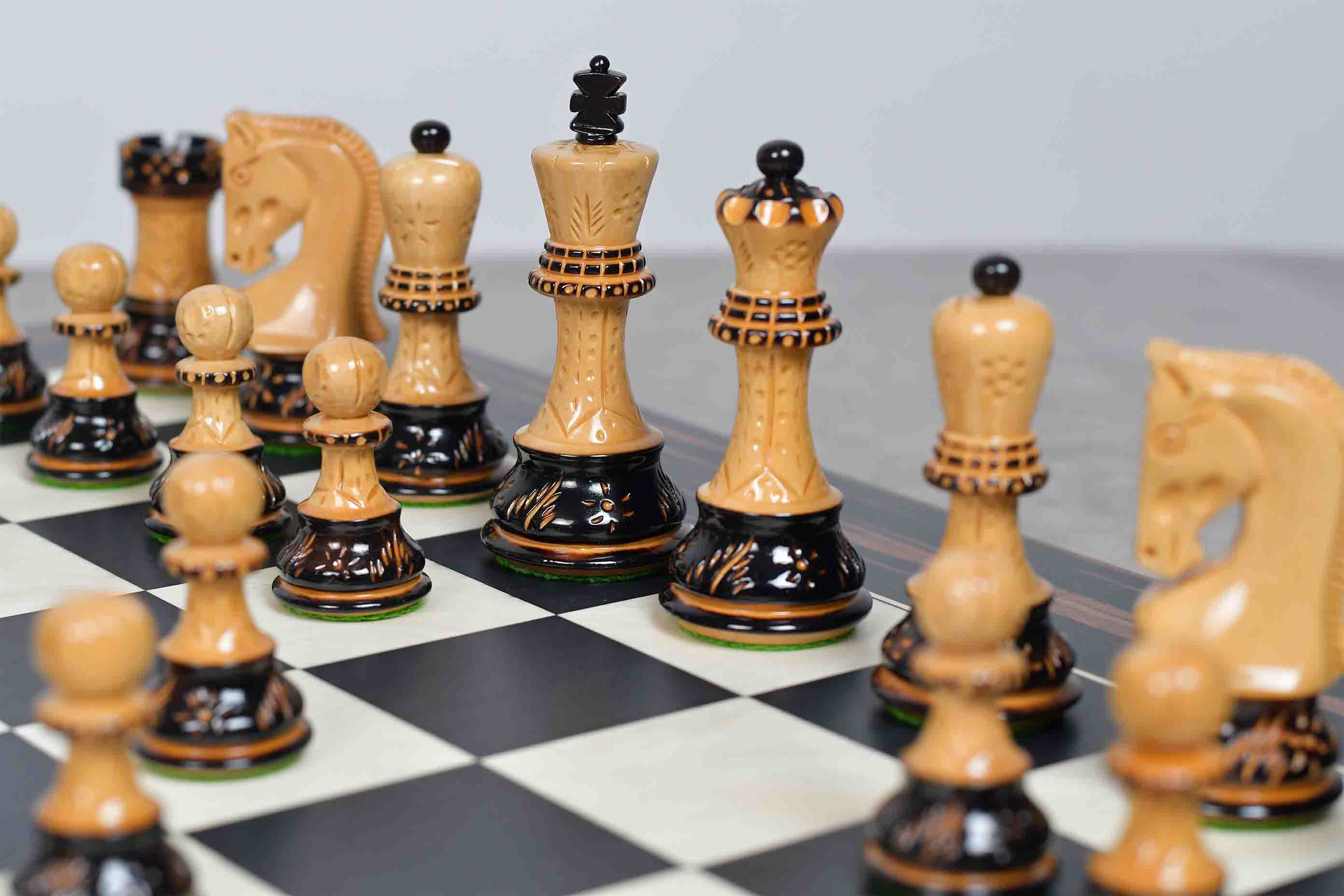 Burnt boxwood chess pieces set up for play on the included 55cm poplar and white erable board