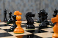 Genuine ebony chess pieces set up for play on the included 58cm ebony and maple board with a sheesham border