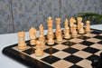 Ebonised chess pieces set up for play on the included 48cm solid ebony and maple board