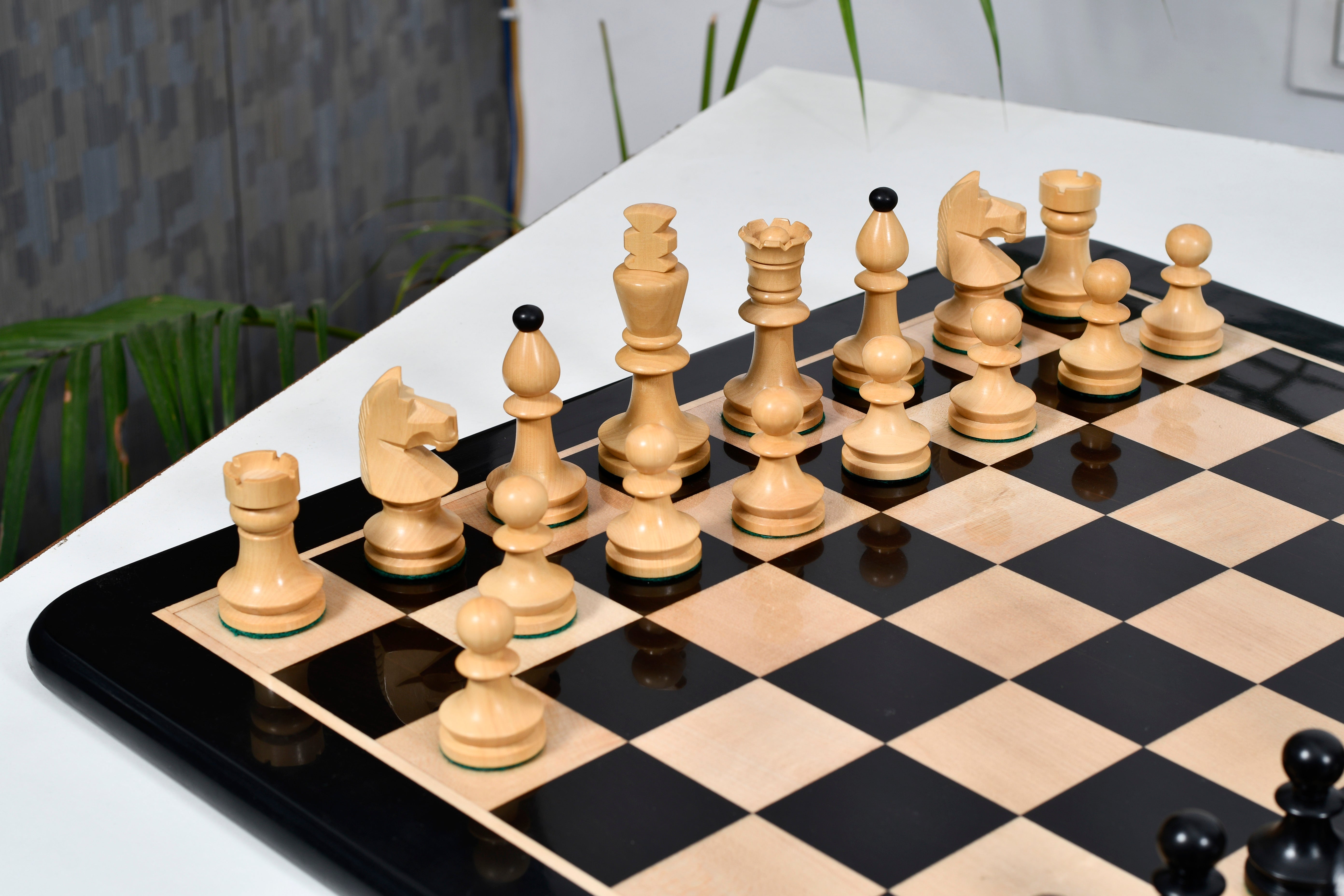 Ebonised chess pieces set up for play on the included matching wooden board