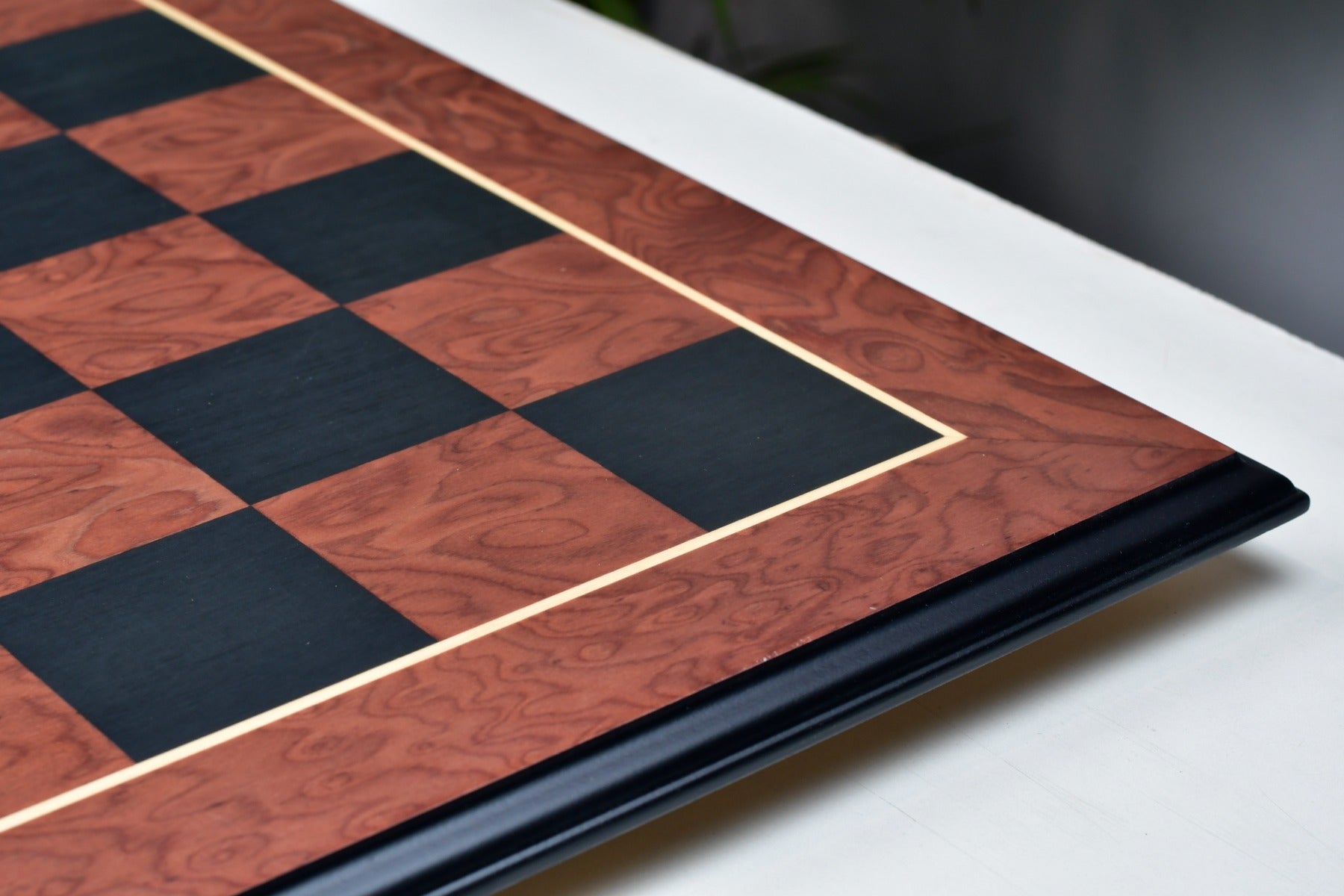 Moulded edge black anigre and red ash burl chess board, edge view