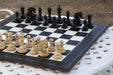 Genuine ebony chess pieces set up for play on the included 60cm black anigre and maple board