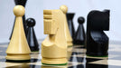 Ebonised chess pieces set up for play on the included 48cm ebony and maple board