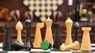 Ebonised chess pieces set up for play on the included 45cm black anigre and maple board