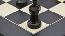 Ebonised chess pieces set up for play on the included 60cm black anigre and maple board