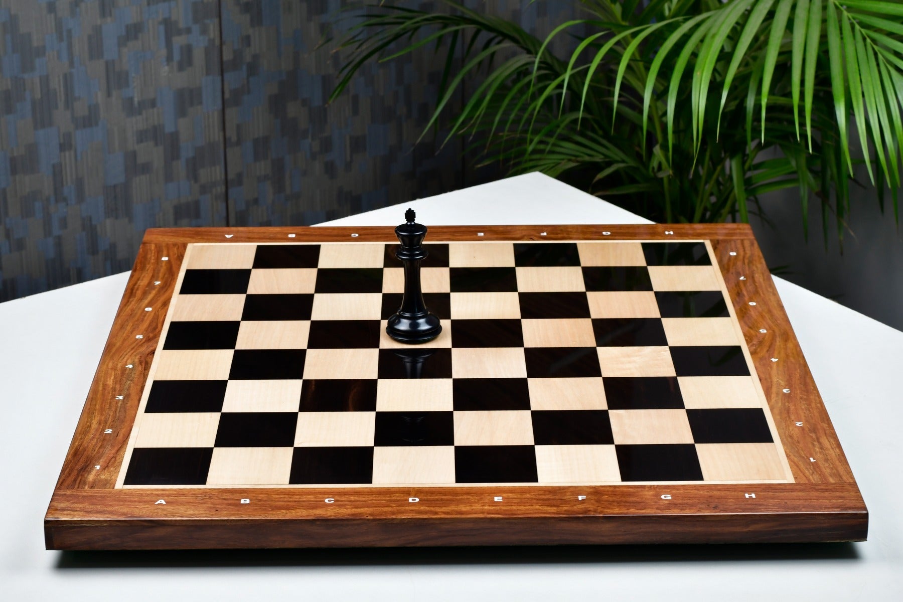 Ebony and maple notation chess board showing its 22mm thickness