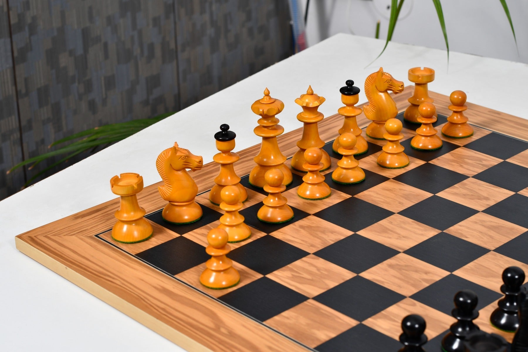Ebonised chess pieces set up for play on the included 55cm black dyed poplar and olive board